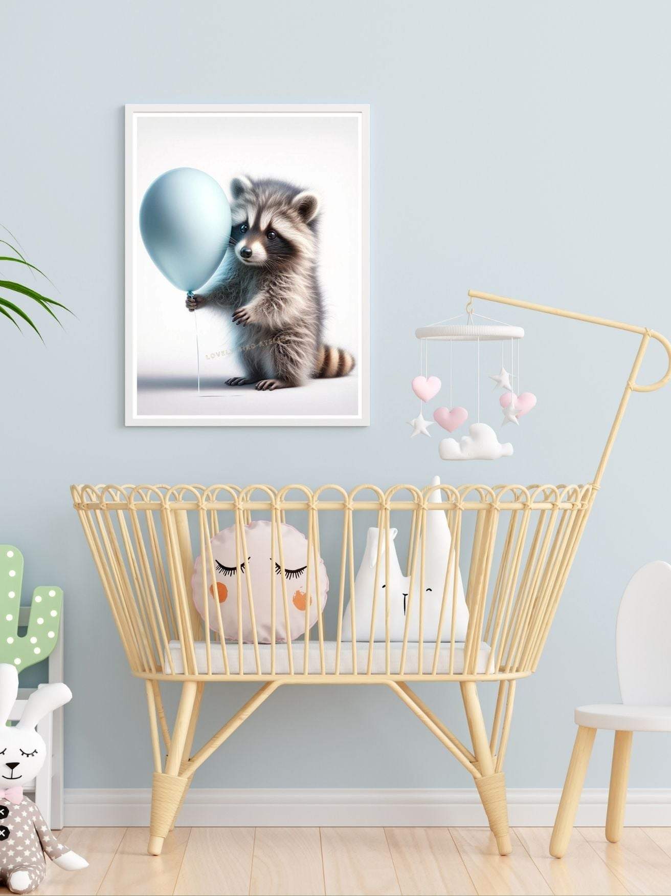 Chambre de bébé avec un berceau en osier, affiche d'un raton laveur tenant un ballon bleu, et jouets mignons de peluche.